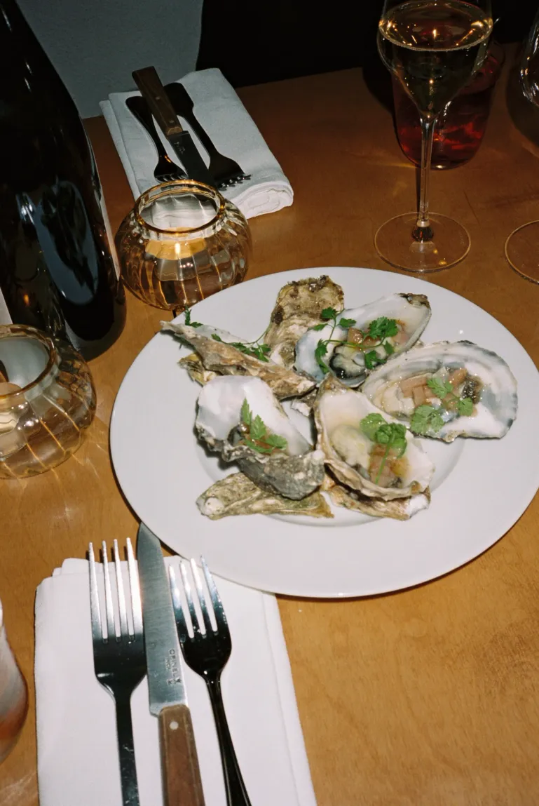 table setting with a plate with oysters, a bottle of wine and a champagne flute