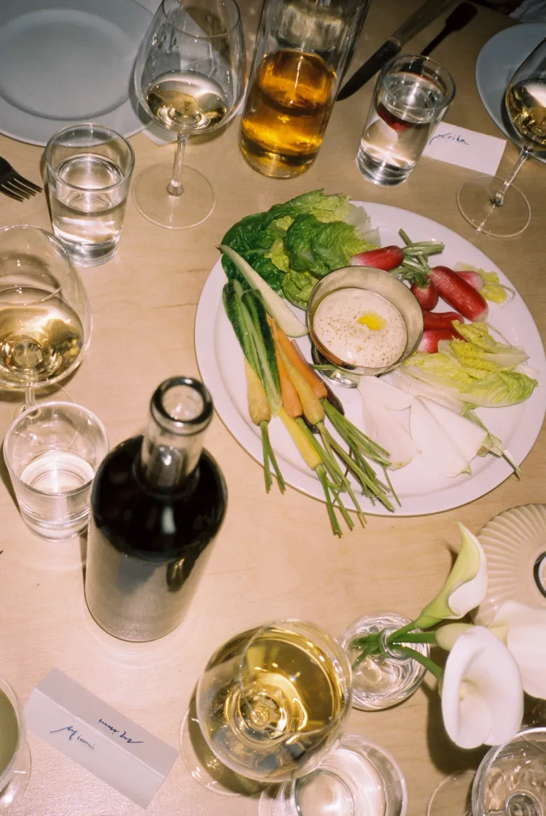 table with plate of crudités, glasses of wine and a bottle of red wine