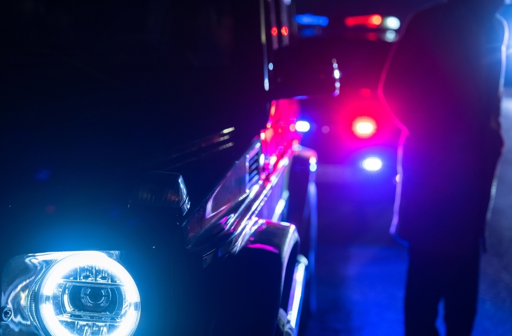 Image Flashing blue and red police lights at a Maryland DUI checkpoint on a rainy night.