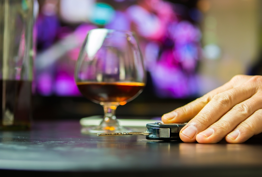 Image Hand reaching for car keys beside a glass of alcohol, representing the risks of drunk driving during Thanksgiving in Maryland.