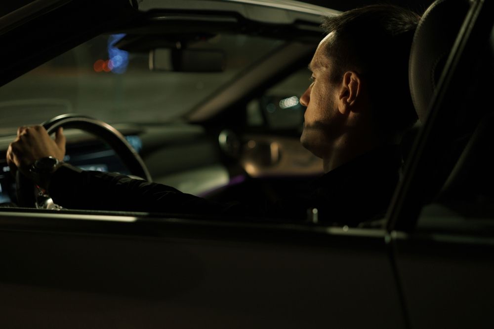 Man sitting in the driver's seat of a car at night holding the steering wheel, illustrating Maryland actual physical control DUI risks.