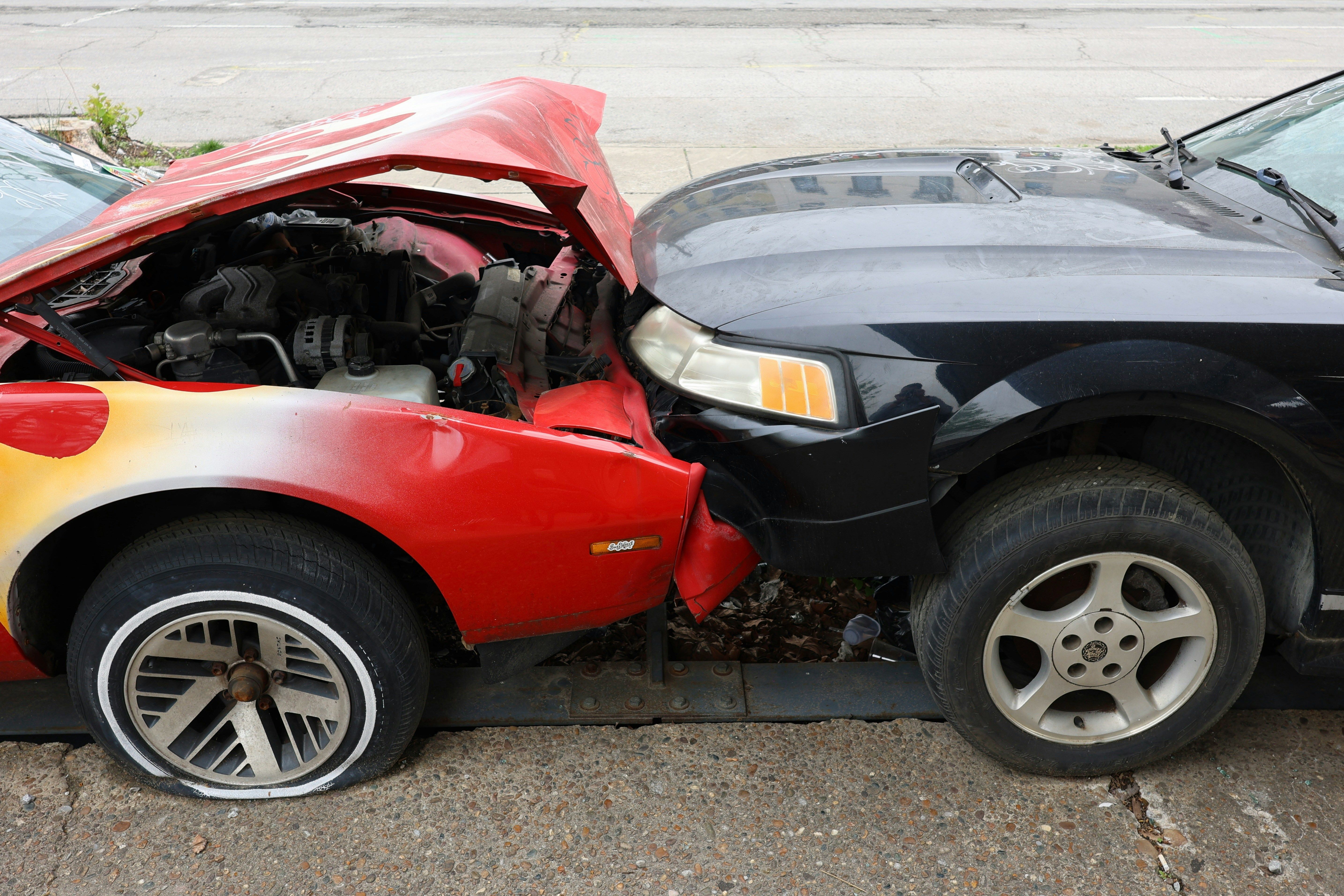 Front-end collision damage between a red flame-decal car and a dark sedan after a Maryland drunk driving crash