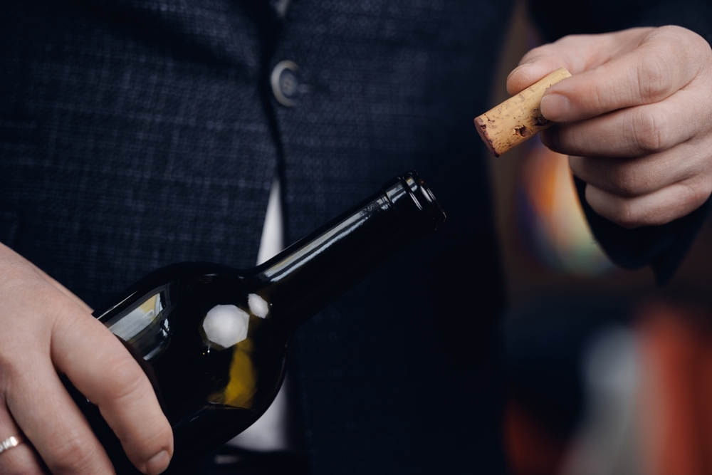 Image Restaurant owner opening wine bottle while preparing for Baltimore liquor license application process
