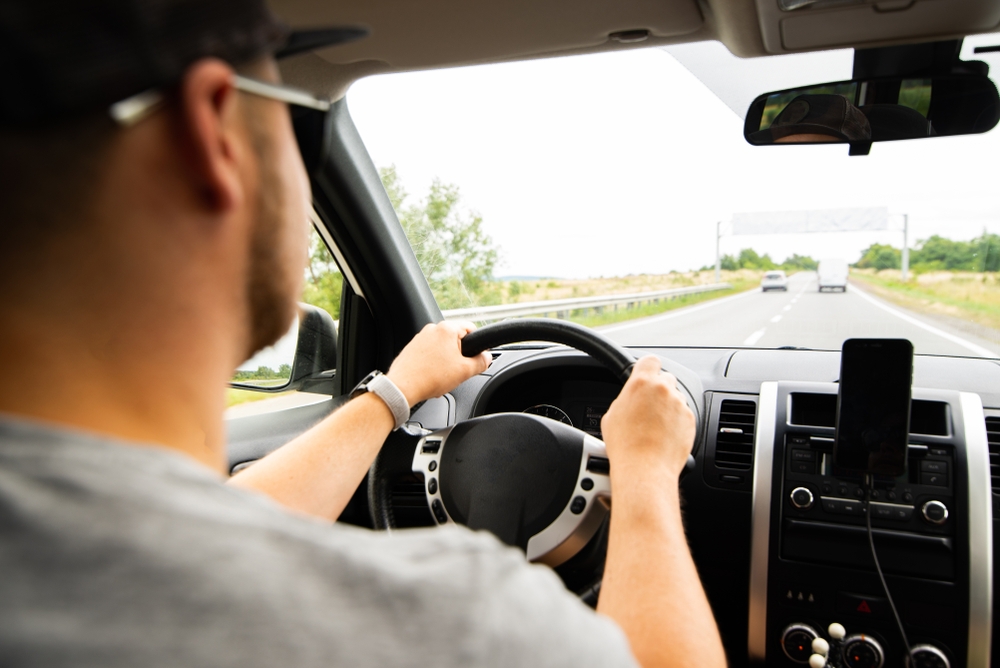 Image A man driving a car on an open highway, illustrating the goal of obtaining a Maryland restricted license after a license suspension to stay on the road for work.