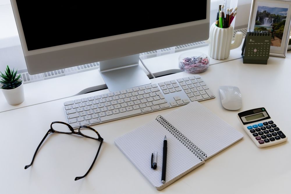 A computer, notebook, calculator, and glasses on a desk, representing the digital evidence at the center of a Maryland child pornography investigation.