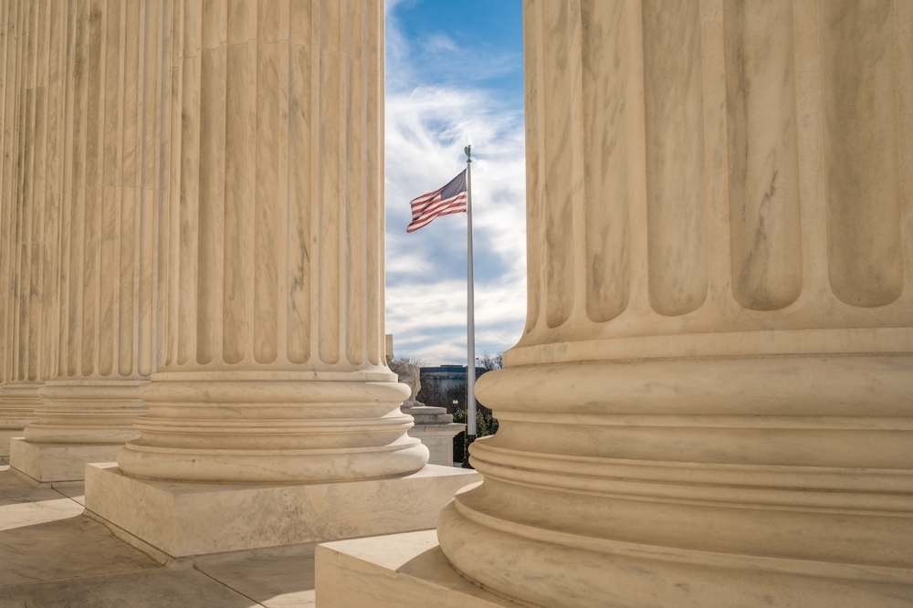Image U.S. flag framed between courthouse columns, representing Maryland constitutional law and the removal of elected officials facing criminal charges.
