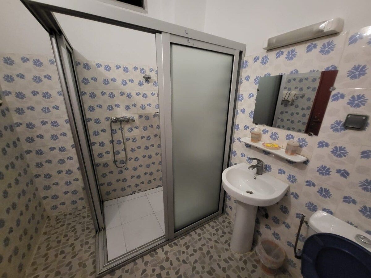 Salle de bain avec douche, lavabo et carrelage floral