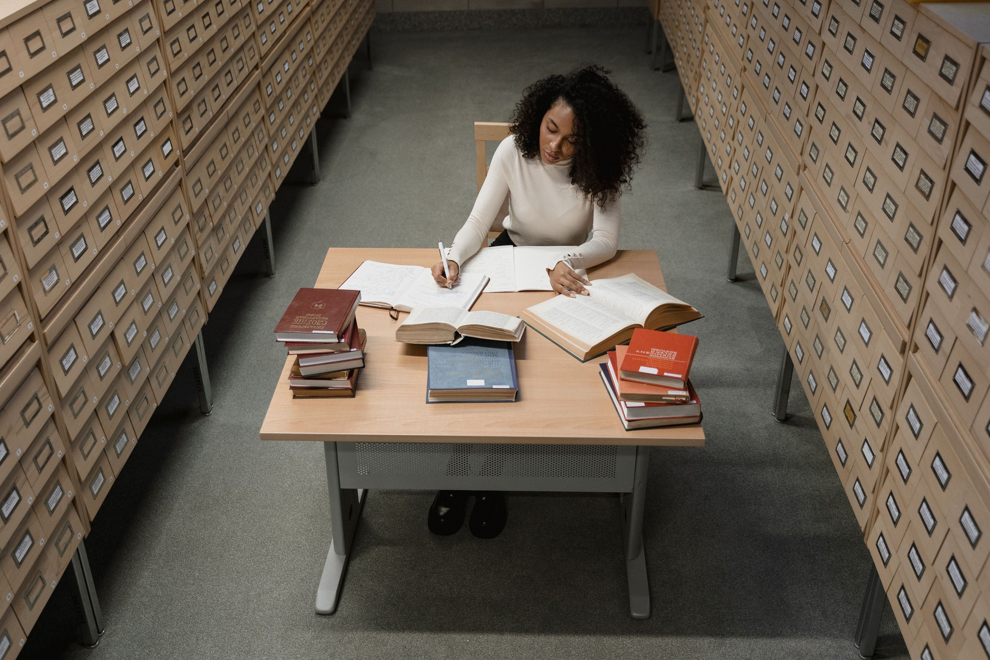 A records officer at work between walls of archive drawers.