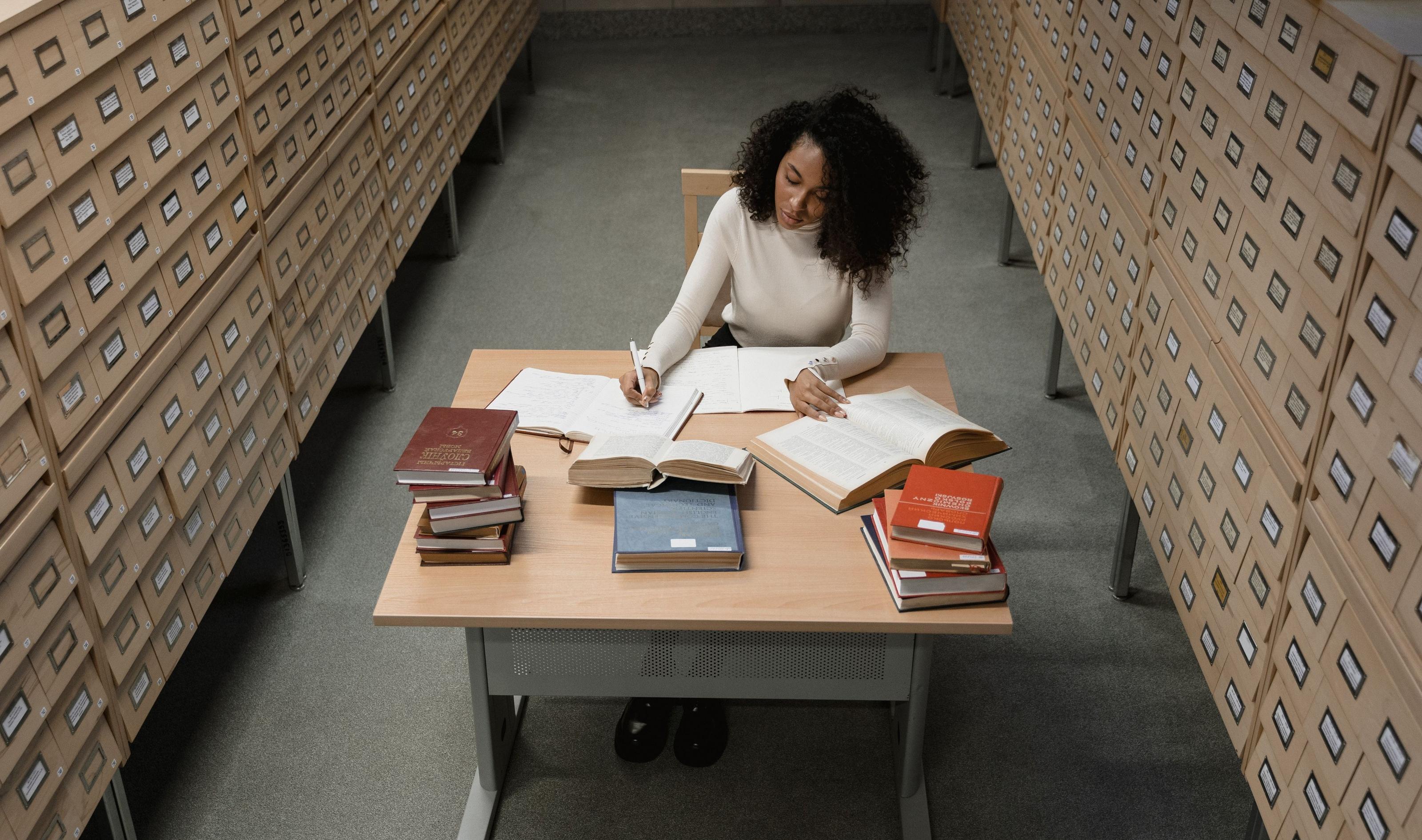 A records officer at work between walls of archive drawers.