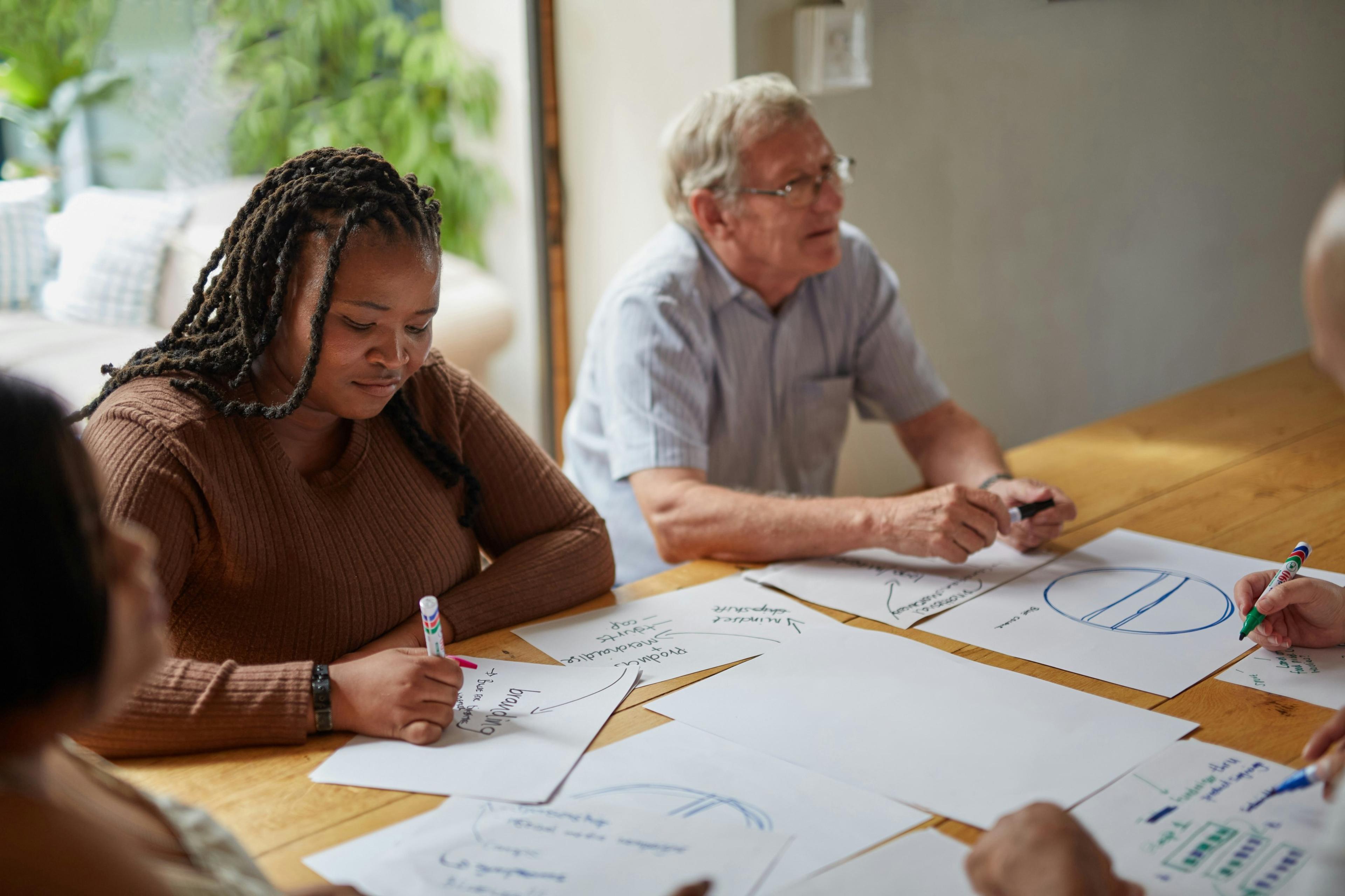 A team workshop around a table, mapping ideas on paper.