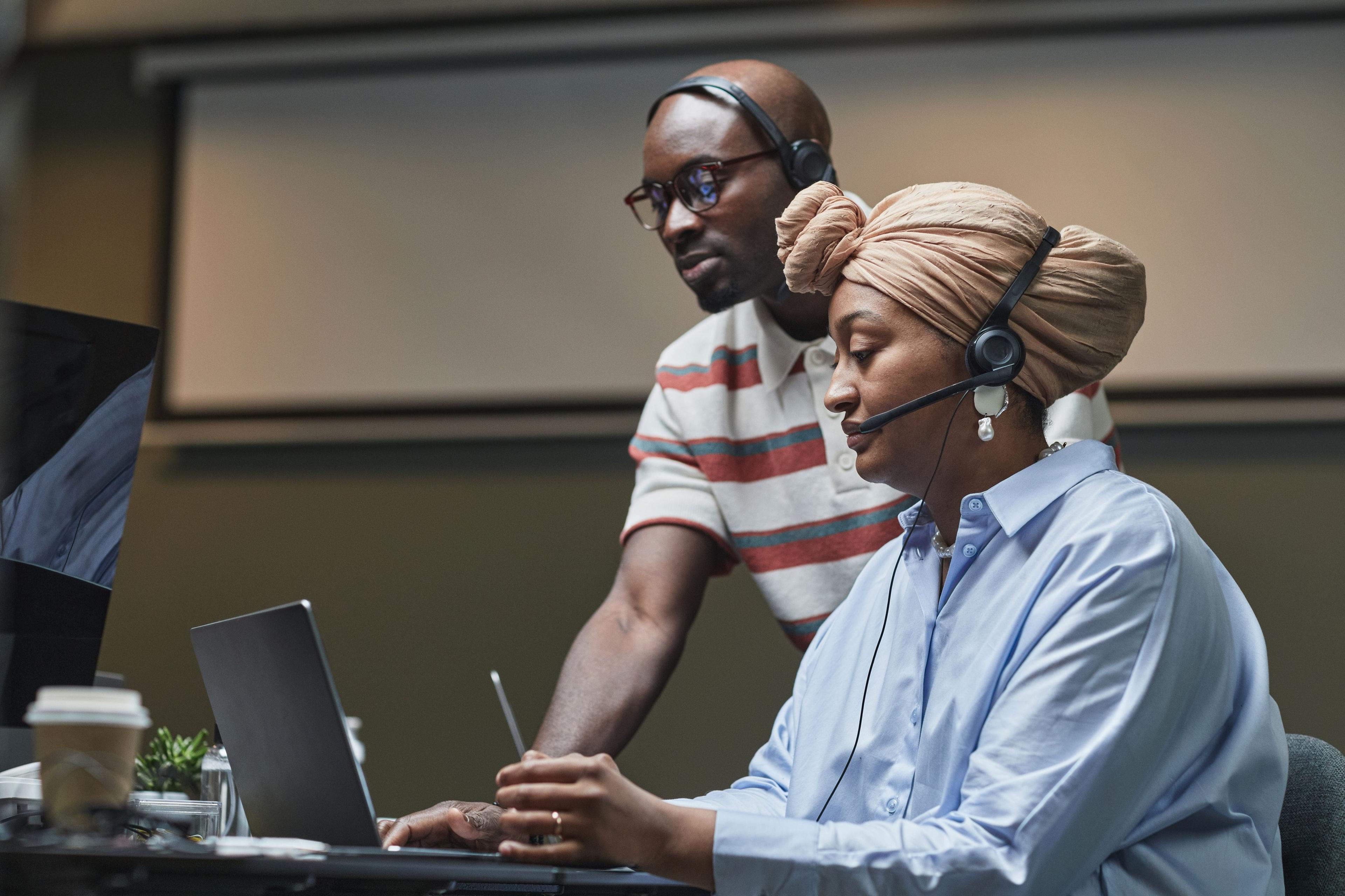 A colleague guiding a teammate through new tools on her laptop.