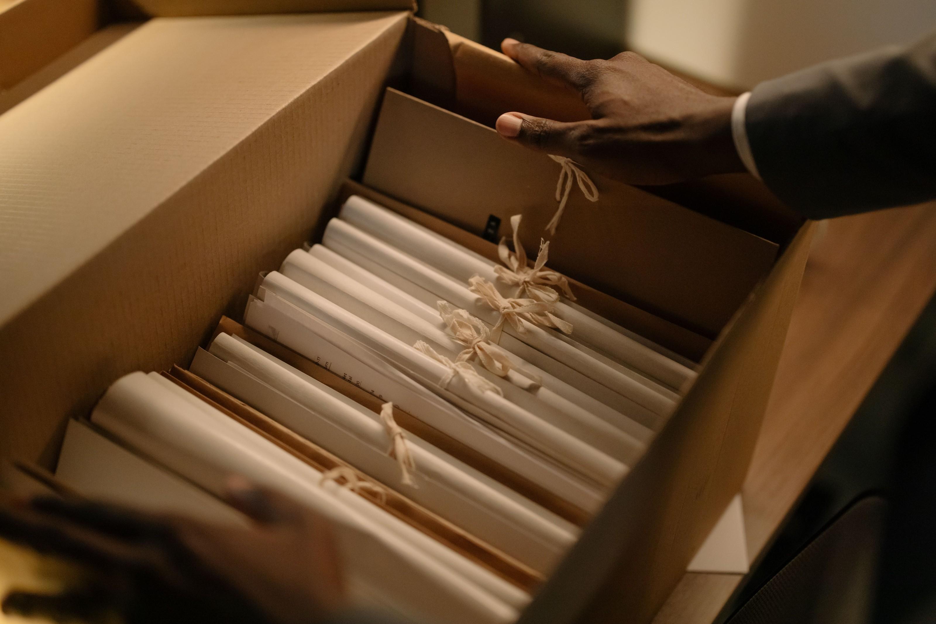 Hands lifting tied files out of an archive box.