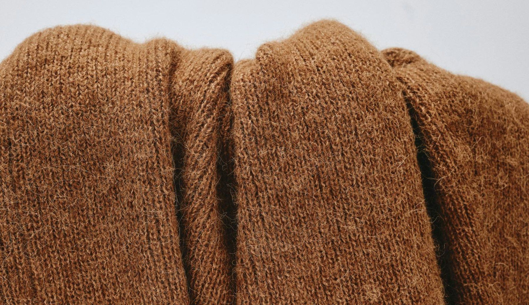 A close crop of folded brown knitted wool, lit to show the ribbing and the fold.