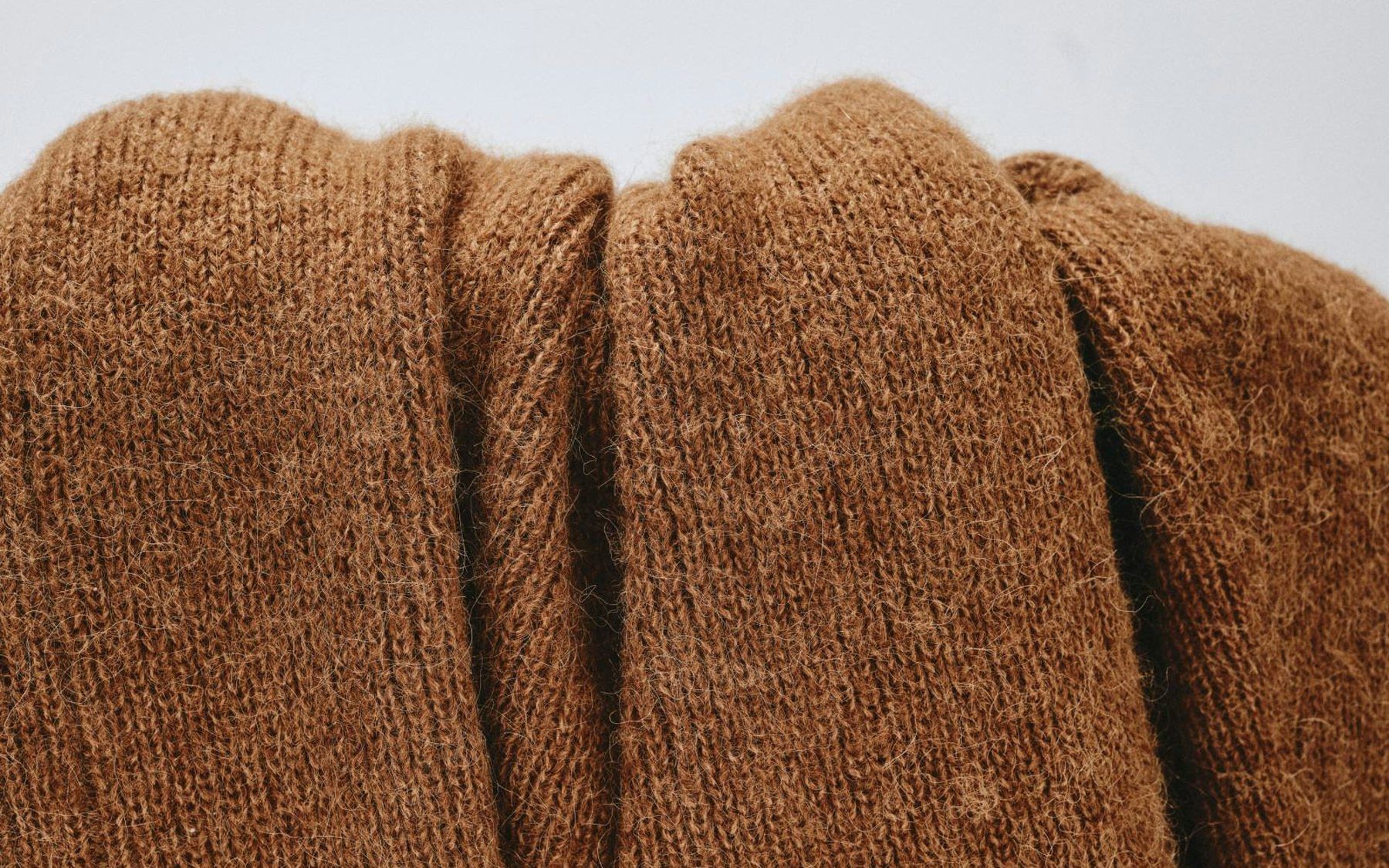 A close crop of folded brown knitted wool, lit to show the ribbing and the fold.