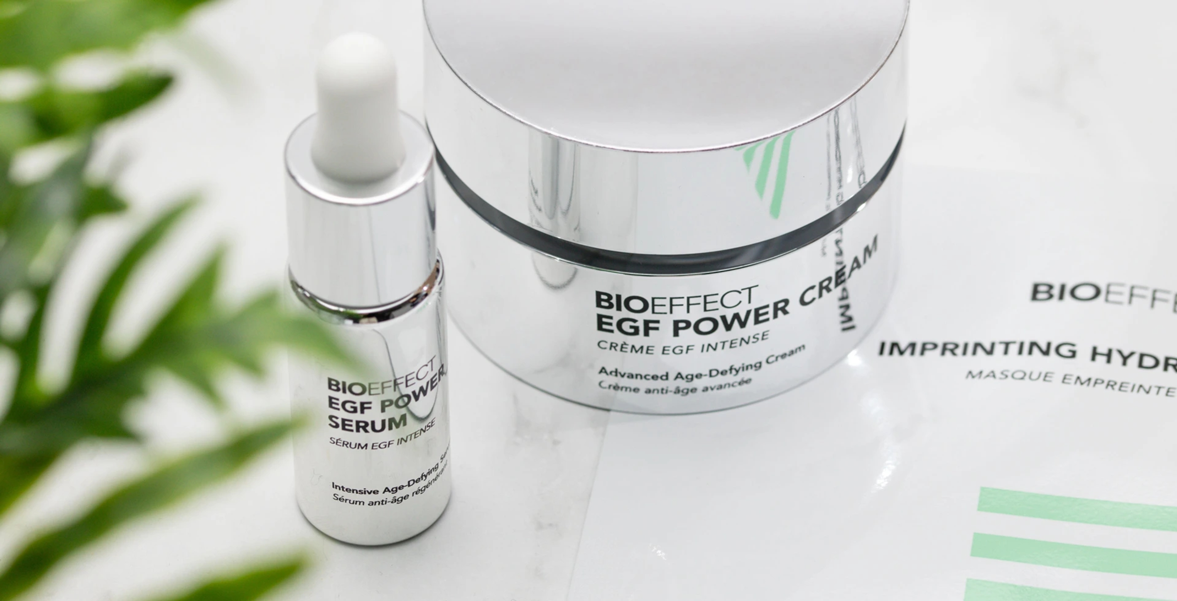 BIOEFFECT Power Cream, EGF Serum, and a hydrating mask on a white surface with a green plant.