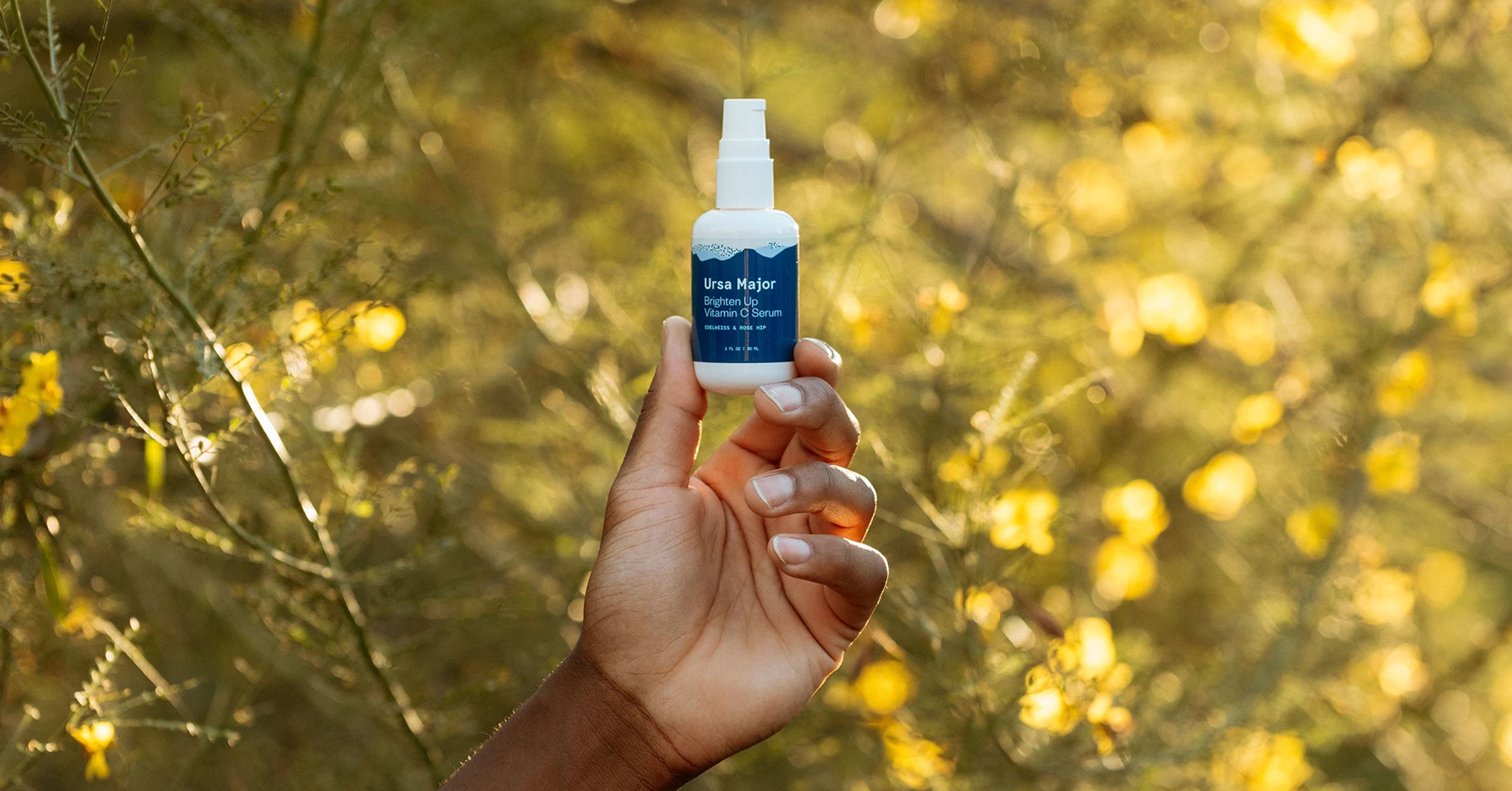 a woman holding a bottle of Ursa Major Vitamin C Serum
