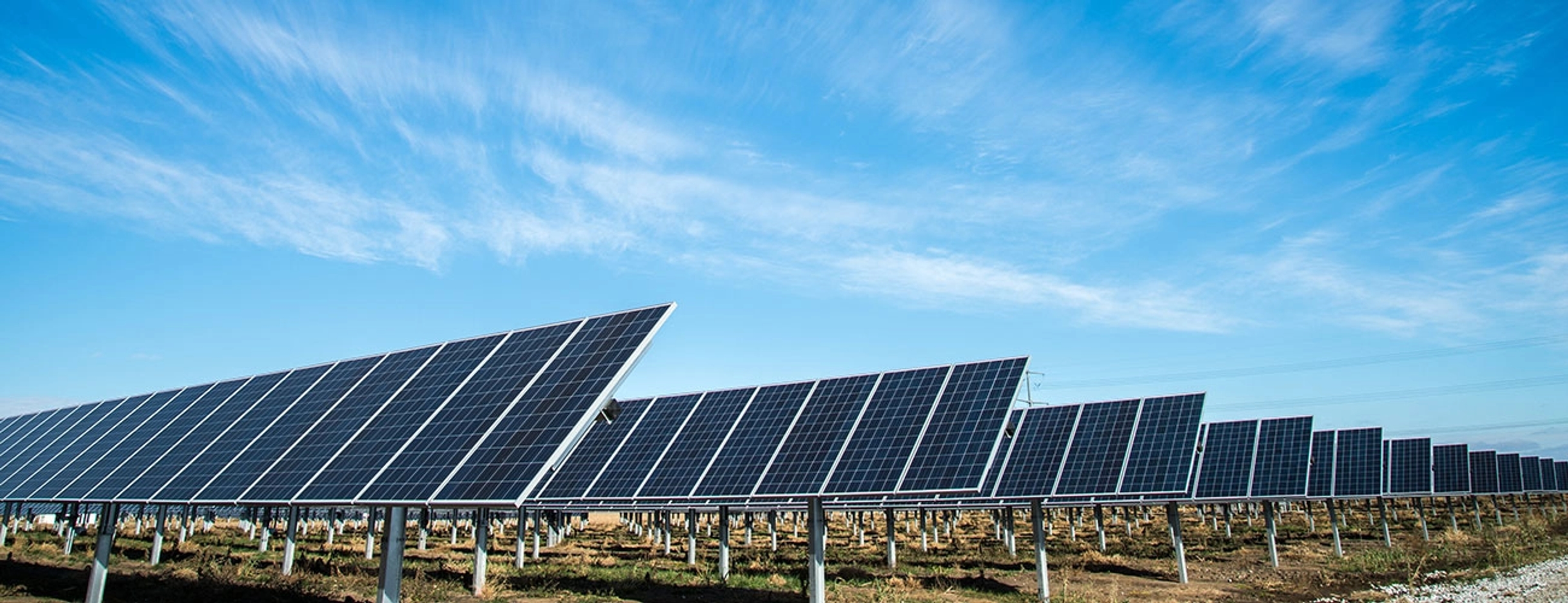 A field of large solar panels pointing towards a blue sky