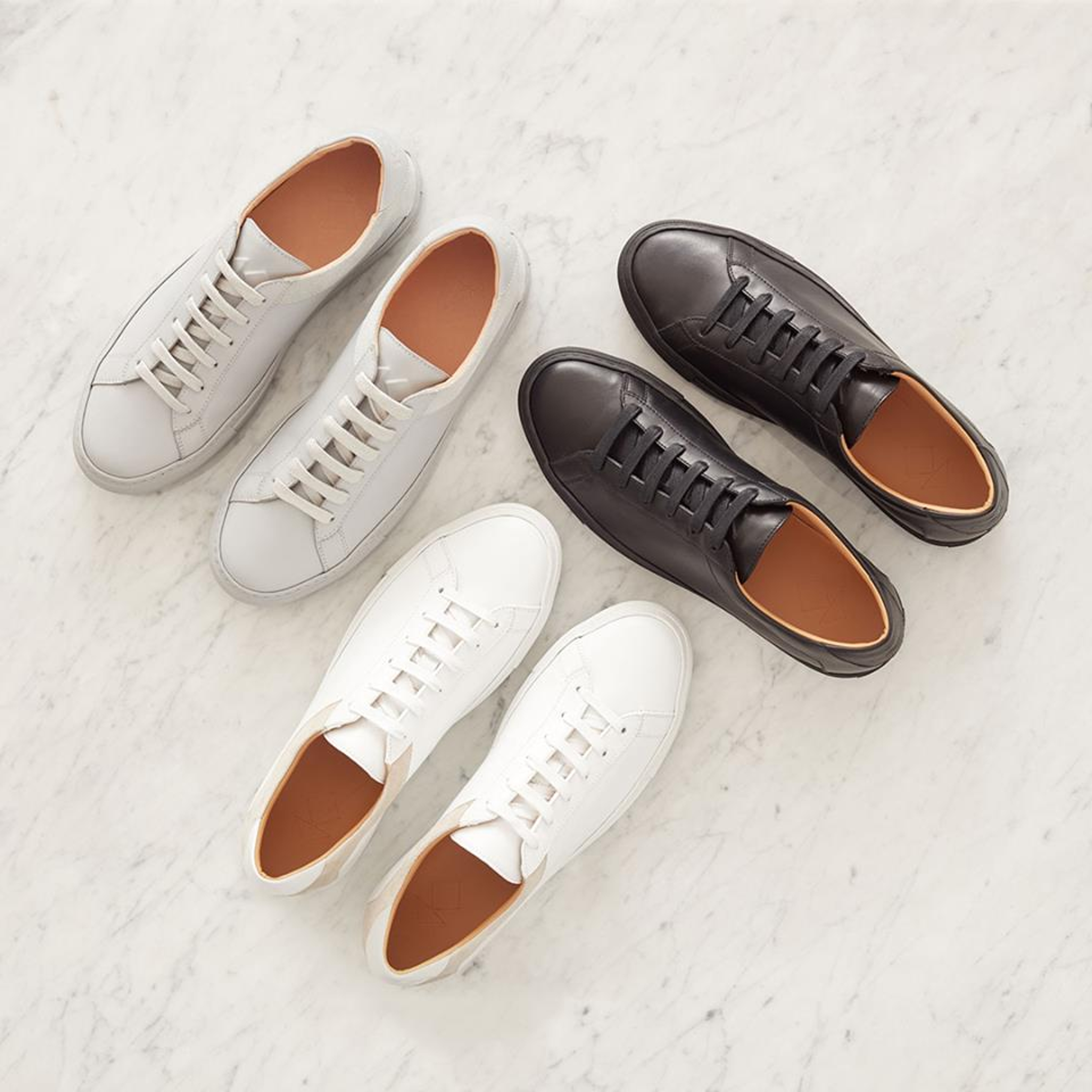 Three pairs of leather shoes: one gray, one white, one black.