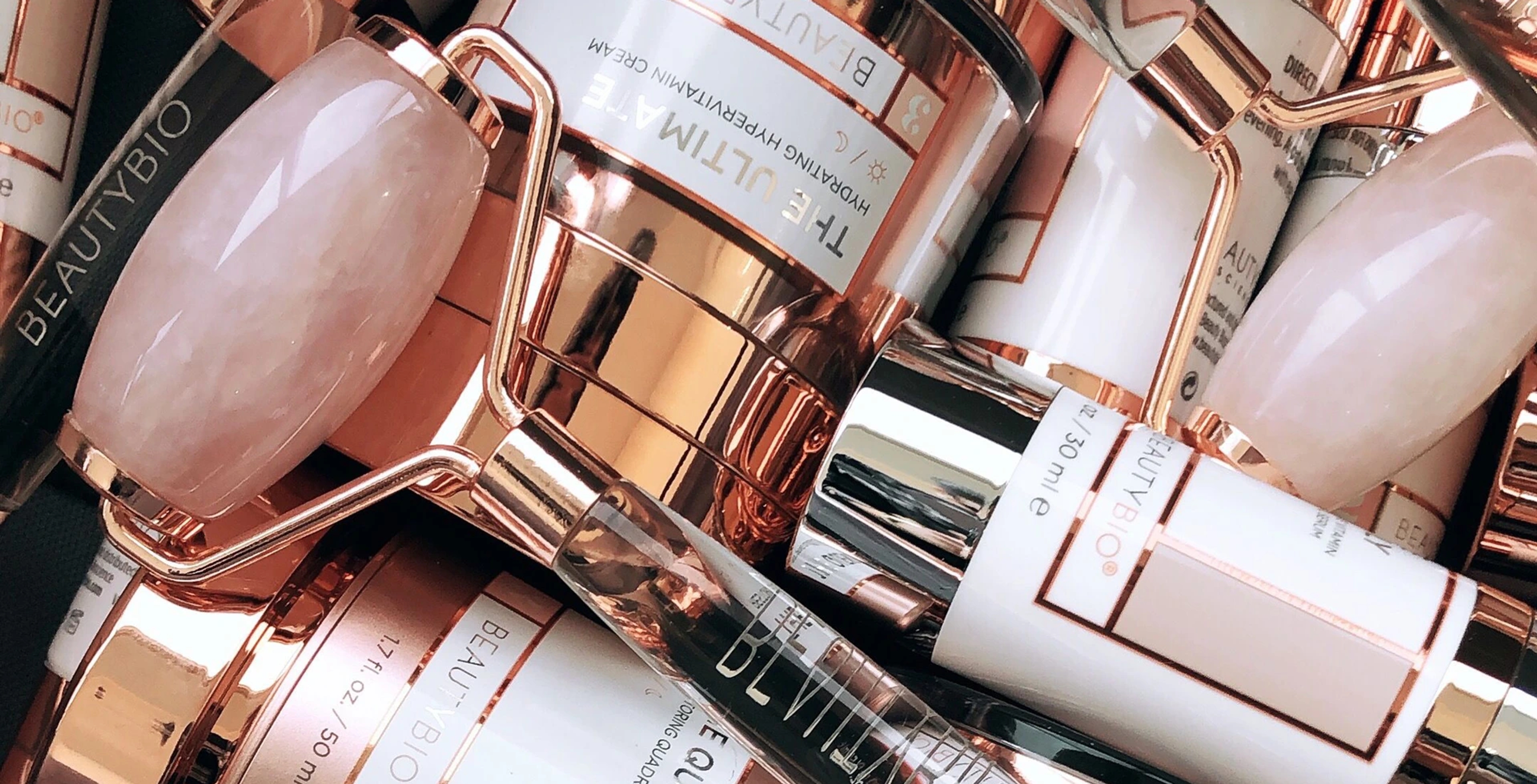 A pile of BeautyBio products with rose gold packaging.