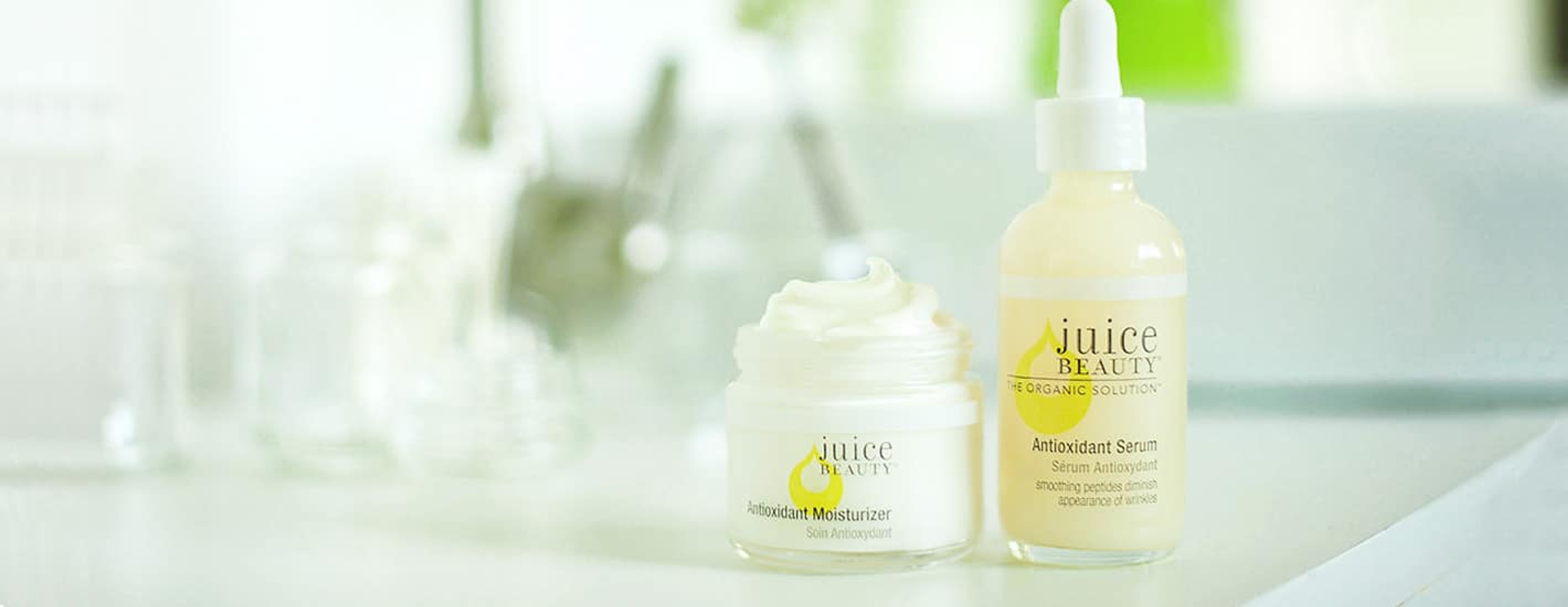 2 bottles of Juice Beauty serum and moisturizer sitting on a counter with natural light shining in from the background