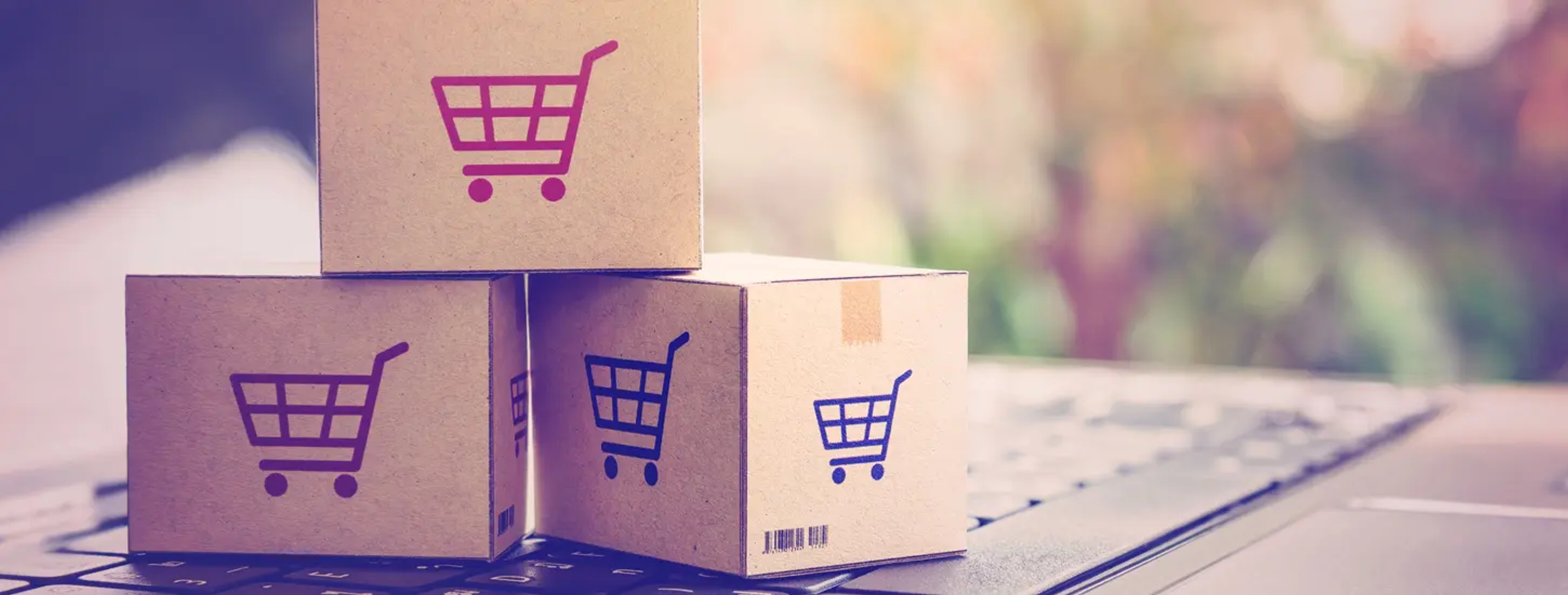 A set of three mini cardboard boxes set on top a laptop representing ecommerce industry