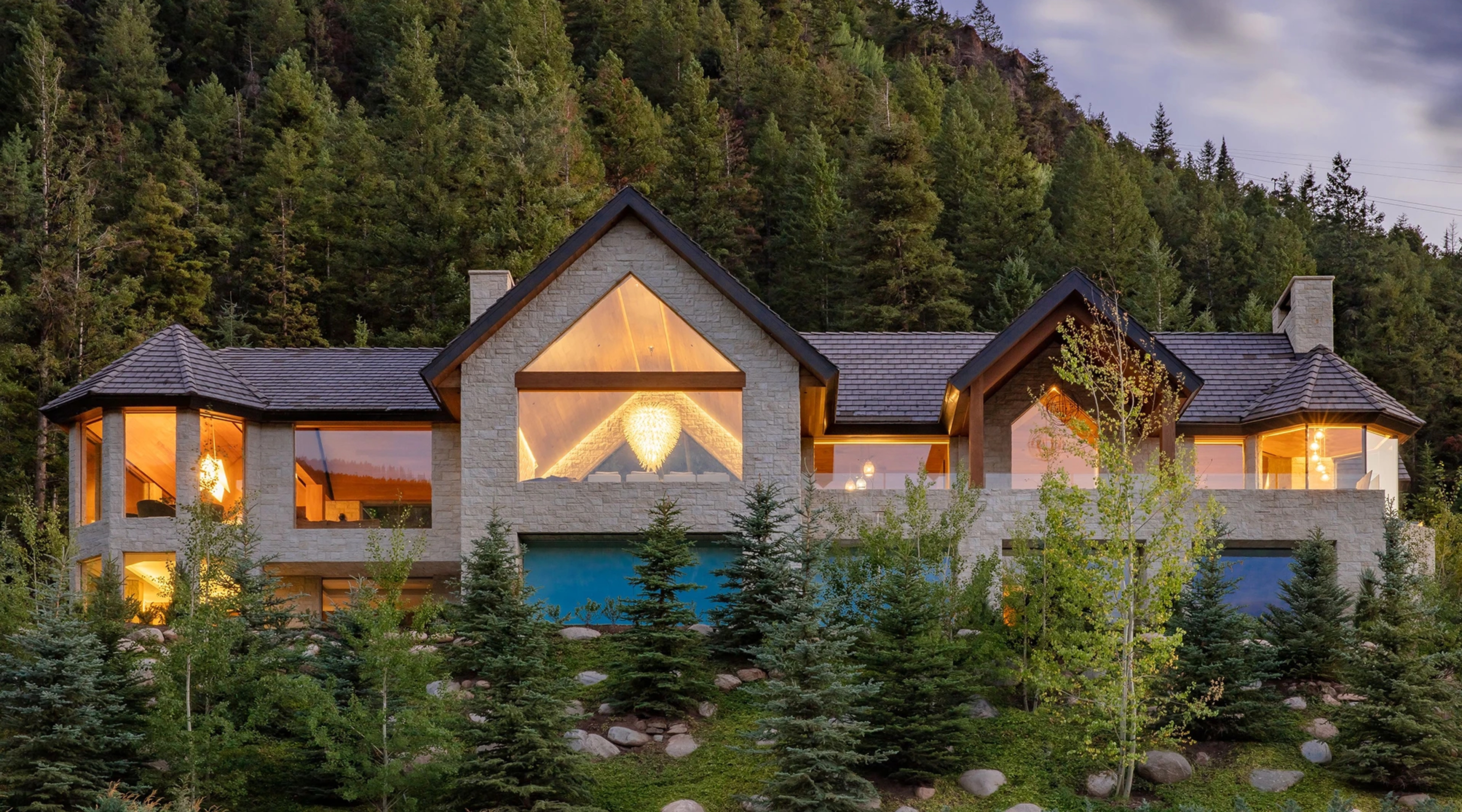A luxury home on a mountain pictured at dusk.