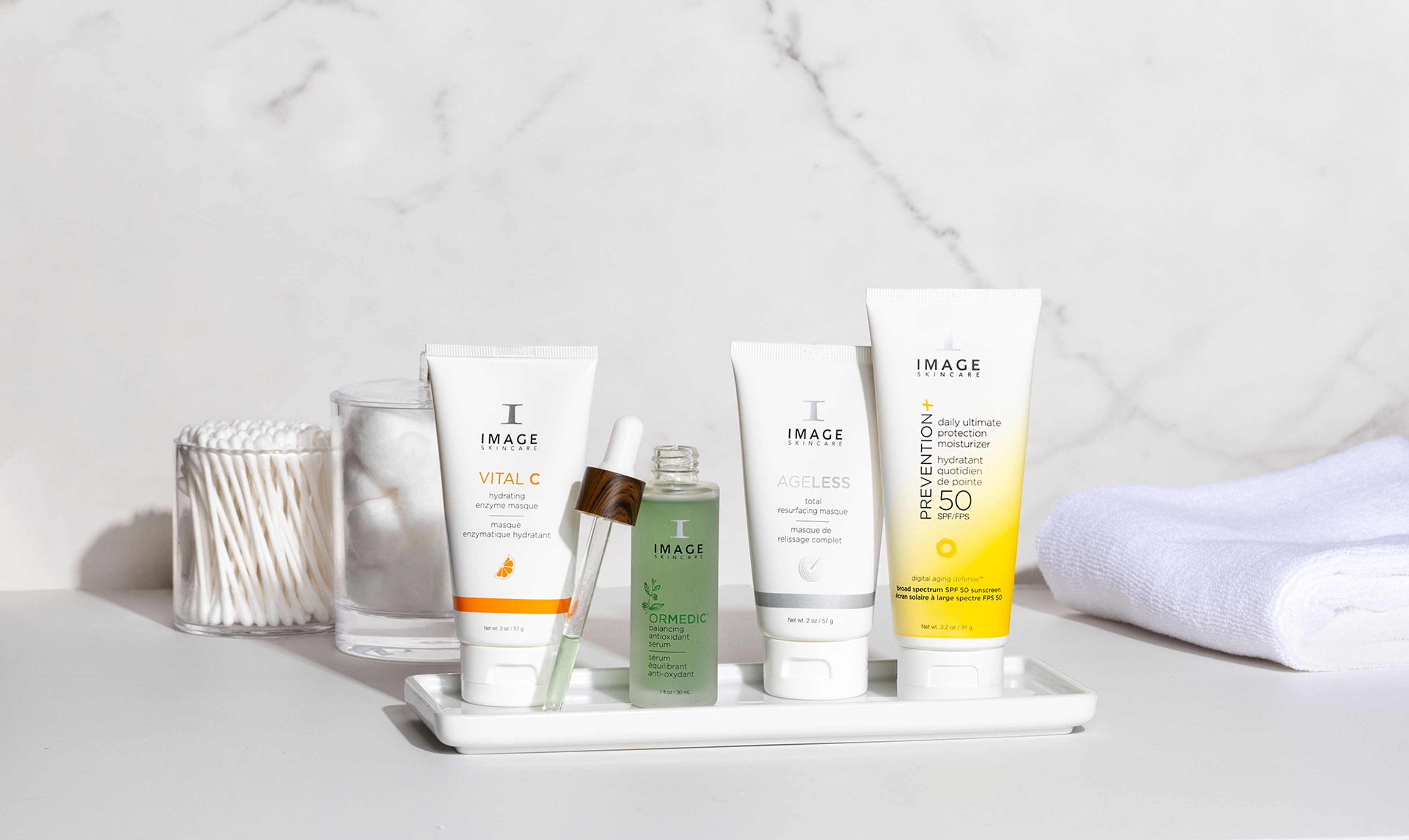 A set of IMAGE Skincare products on a tray near cotton balls, q-tips, and a towel.