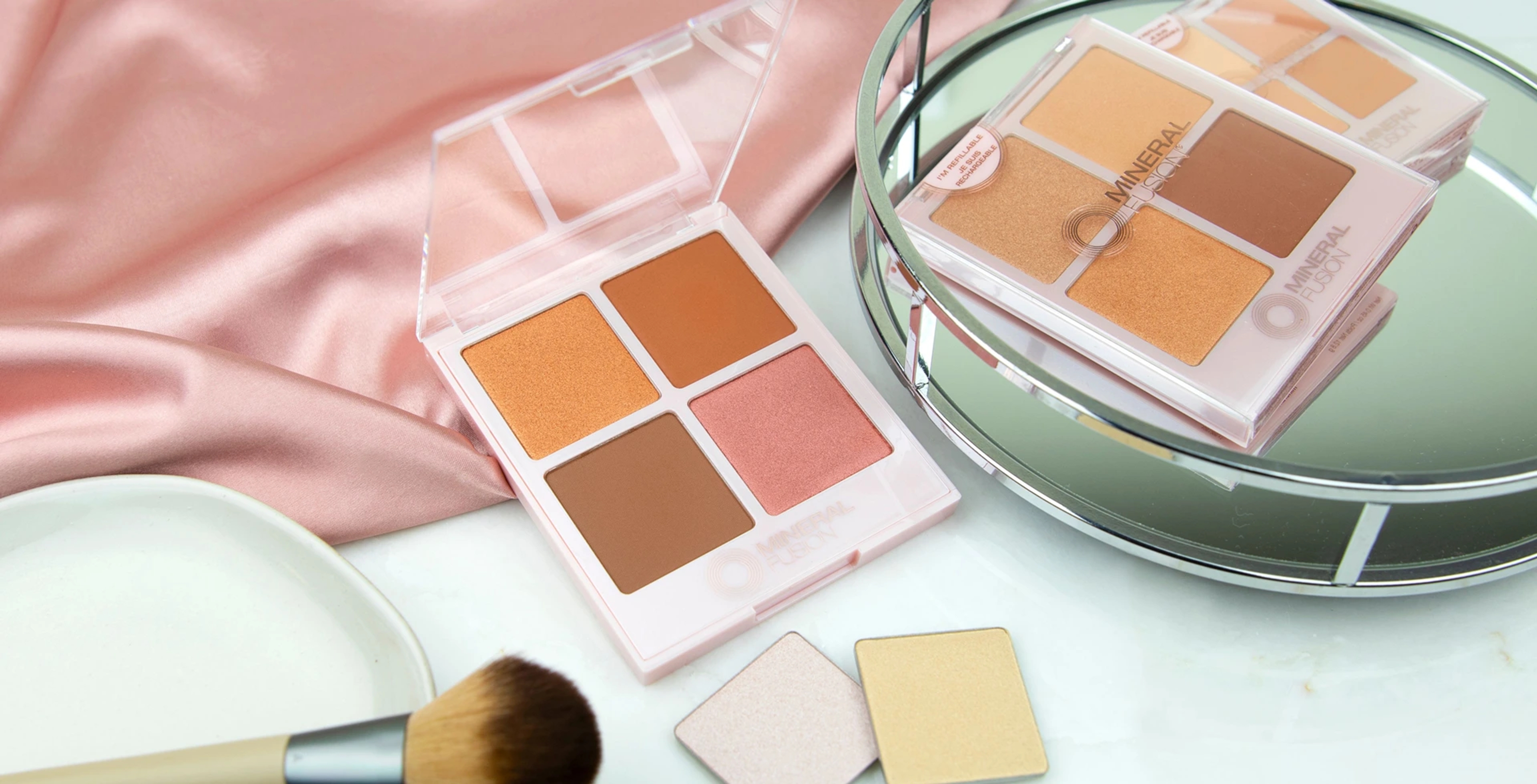 A makeup brush near powder makeup palettes from Mineral Fusion.
