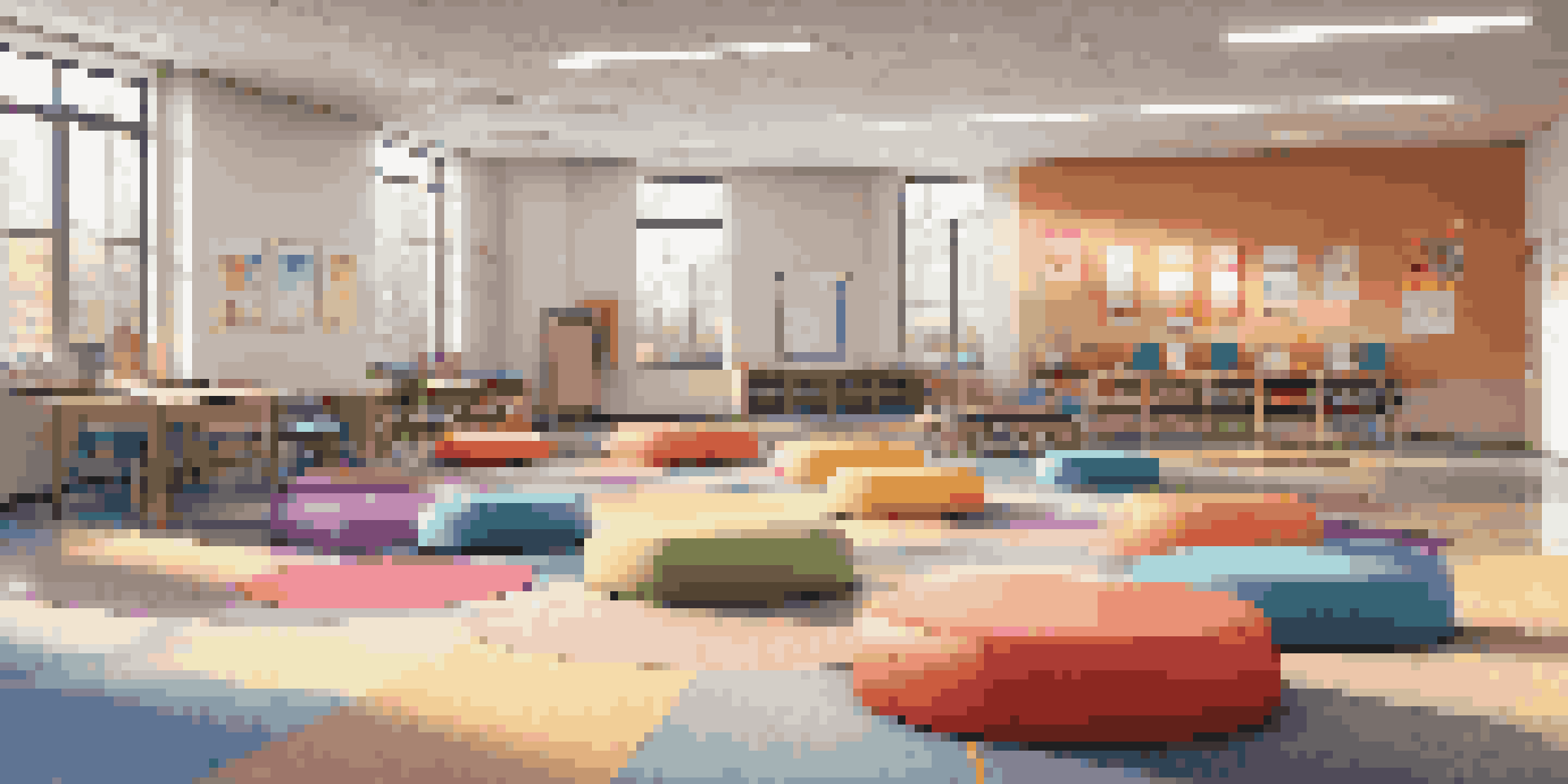 A bright and inviting modern classroom with flexible seating arrangements, including circular desk formation and colorful bean bags, illuminated by natural light from large windows.