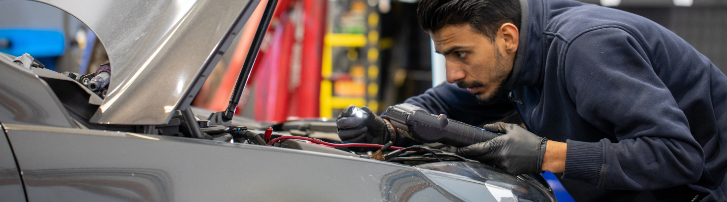 mechanic looking under hood of car