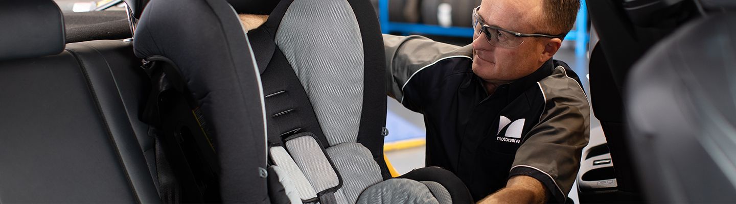 Mechanic fitting child seat in car