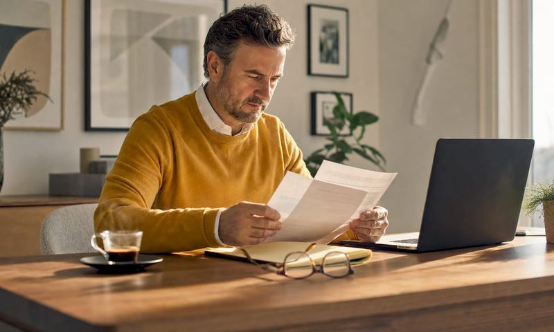 Man reviewing insurance documents at home desk