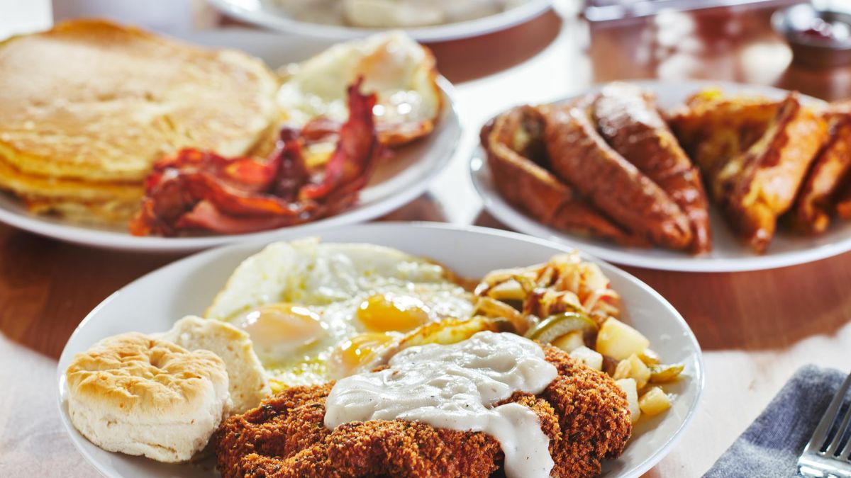 chicken fried steak covered in gravy with sunny side up eggs and breakfast foods