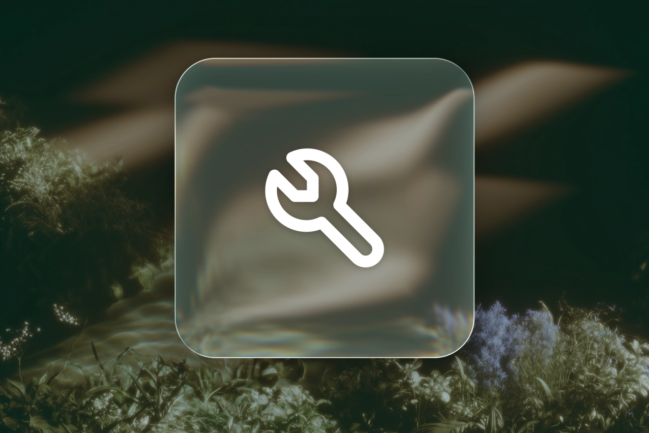 A white wrench icon on a frosted-glass tile against silver-and-amber glass textures.