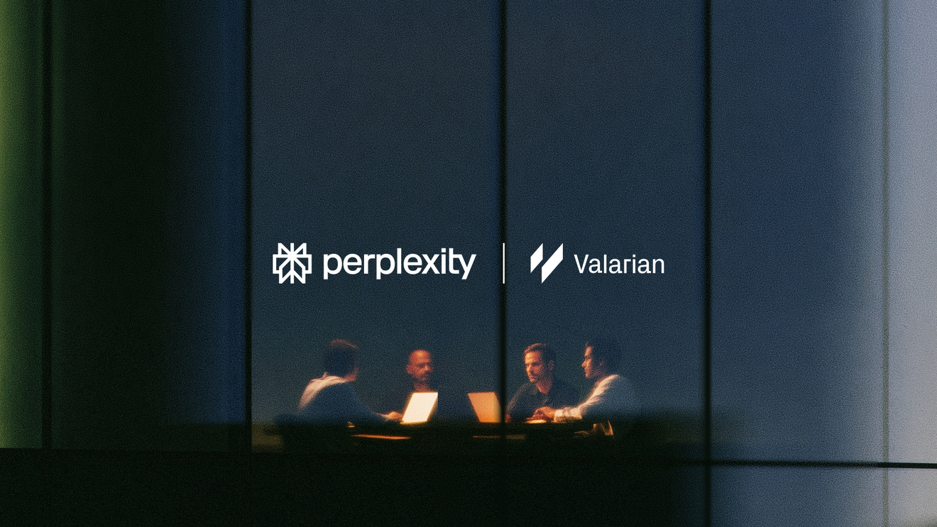Four people working on laptops in a glass-walled meeting room at night.