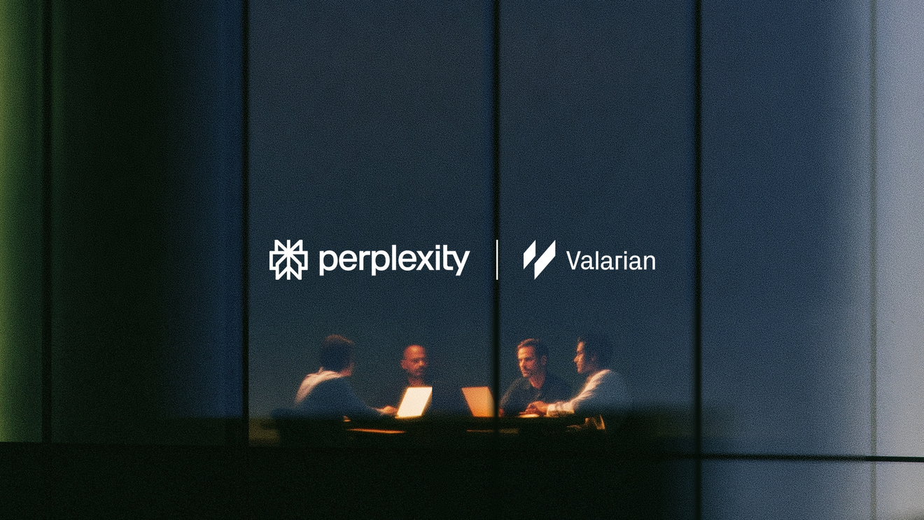 Four people working on laptops in a glass-walled meeting room at night.