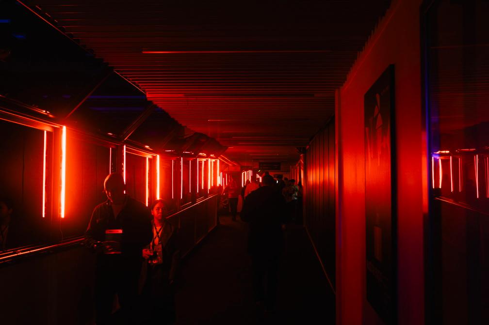 People walk through a dark corridor lit by red neon strips in the Partner Side Event Wing at Slush 2025.