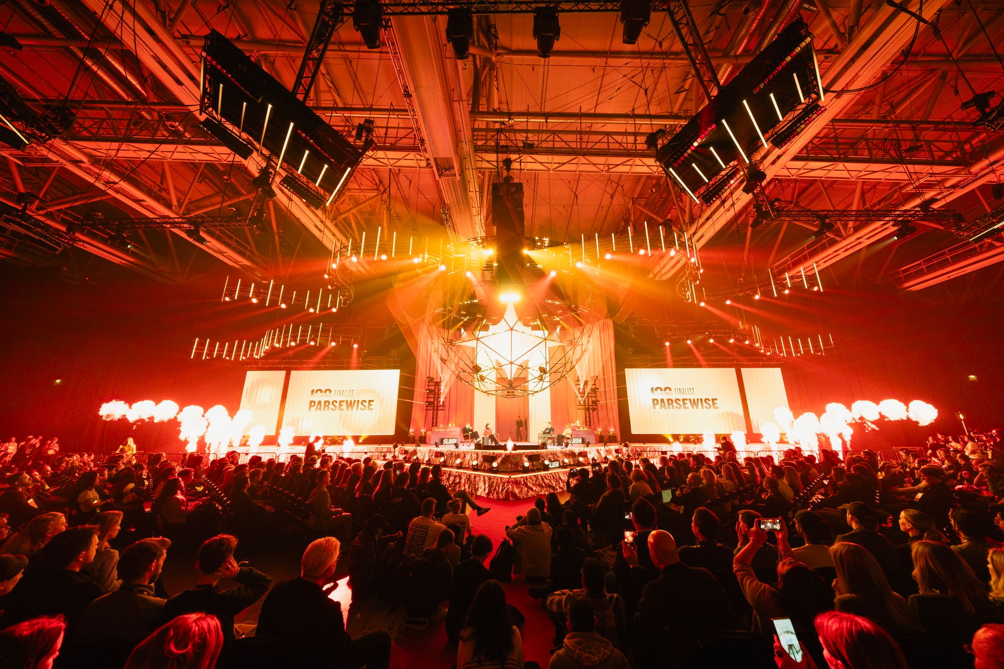 A packed audience faces the Founder Stage, lit in red, during the Slush 100 Finals at Slush 2025 in Helsinki.