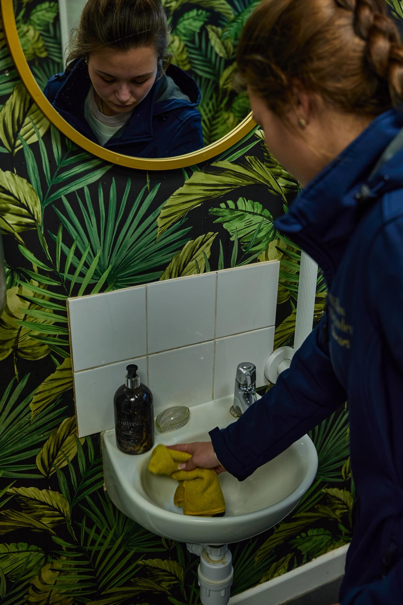 A close-up of chrome bathroom taps in a bright London bathroom with visible limescale around the base before a careful deep clean