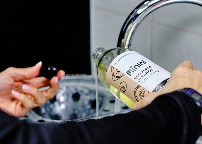 A neat cleaning caddy with low-tox plant-based products and reusable cloths on a bright kitchen worktop in a London home