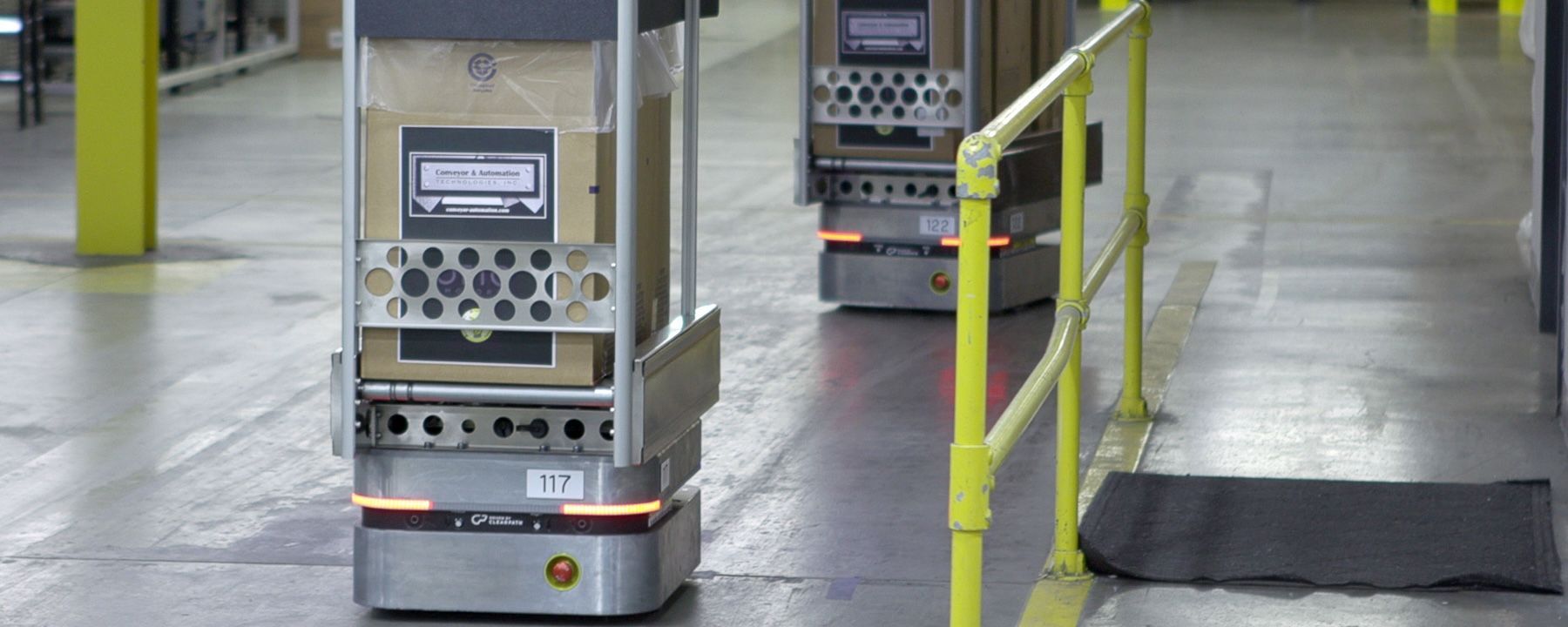 OTTO 100 autonomous mobile robot with conveyor attachment moving boxes on factory floor.