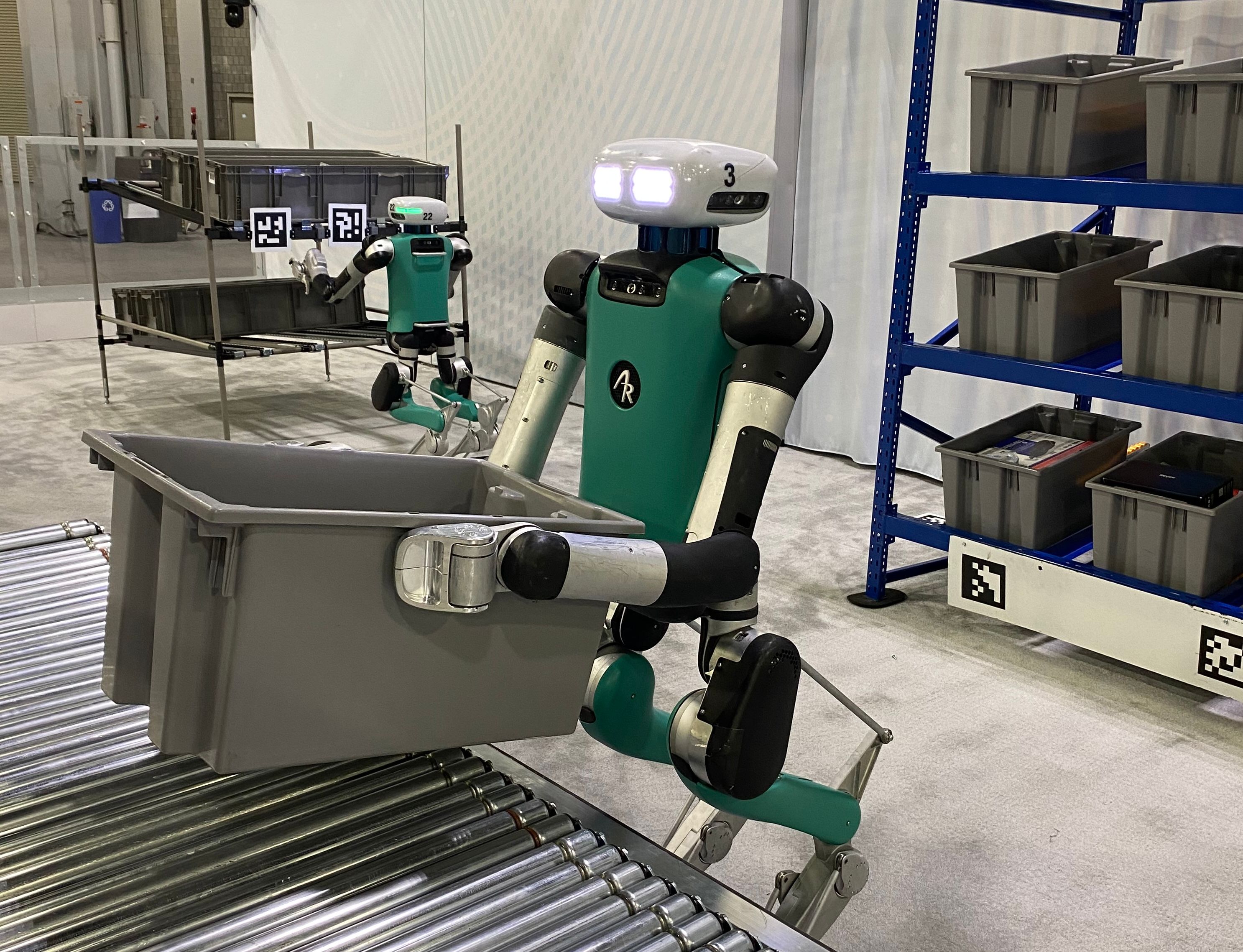 Image 3: Human-size robots moving bins at MODEX 2024.