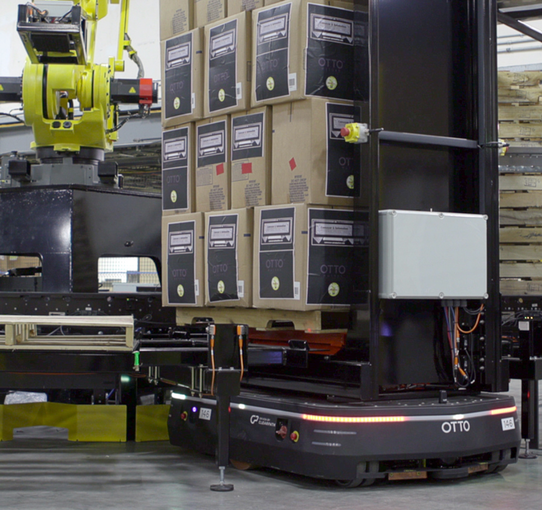 Autonomous mobile robot moving boxes to a palletizing machine at a manufacturing facility.