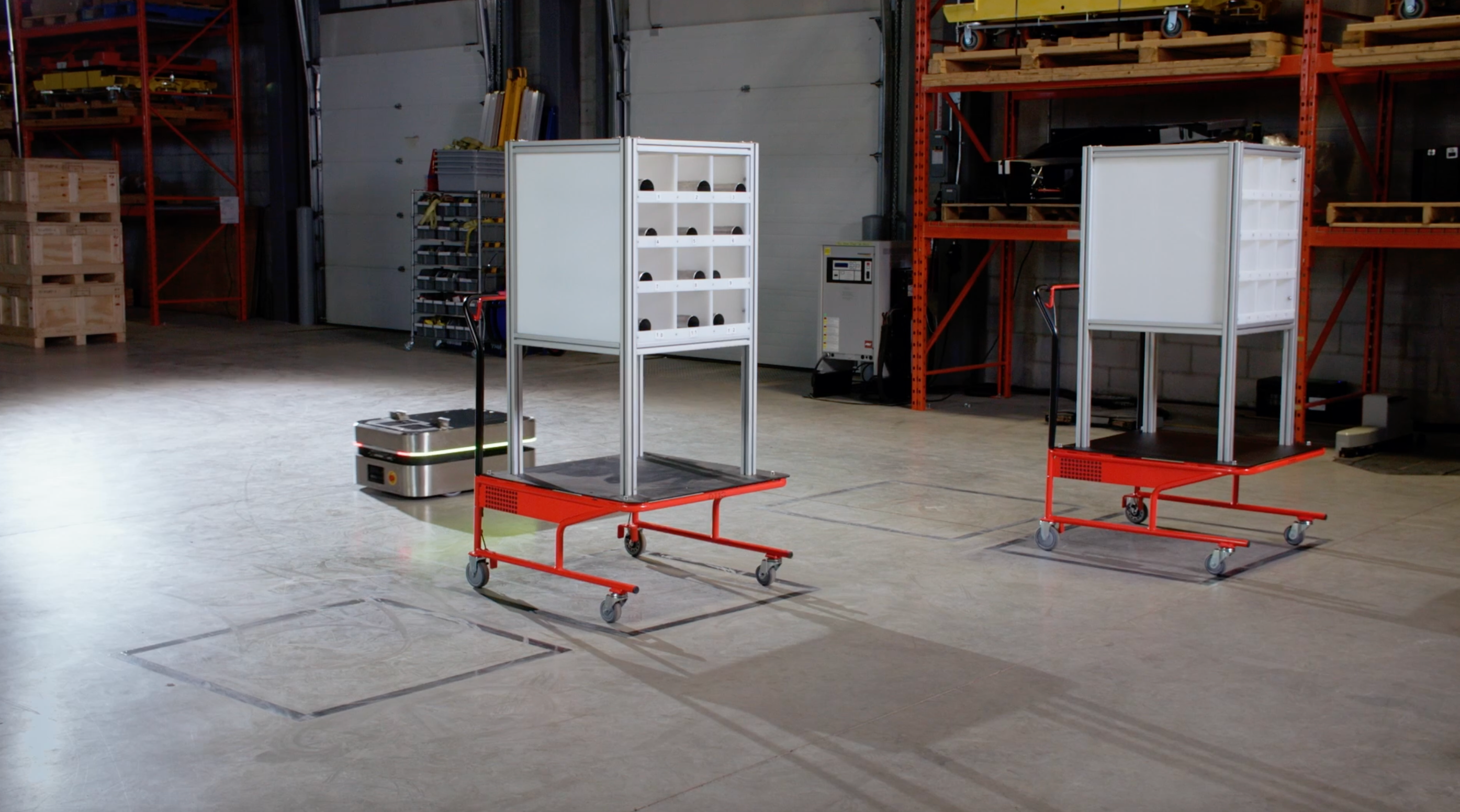 OTTO 100 autonomous mobile robot interacting with red staging cart accessory to move mterials.