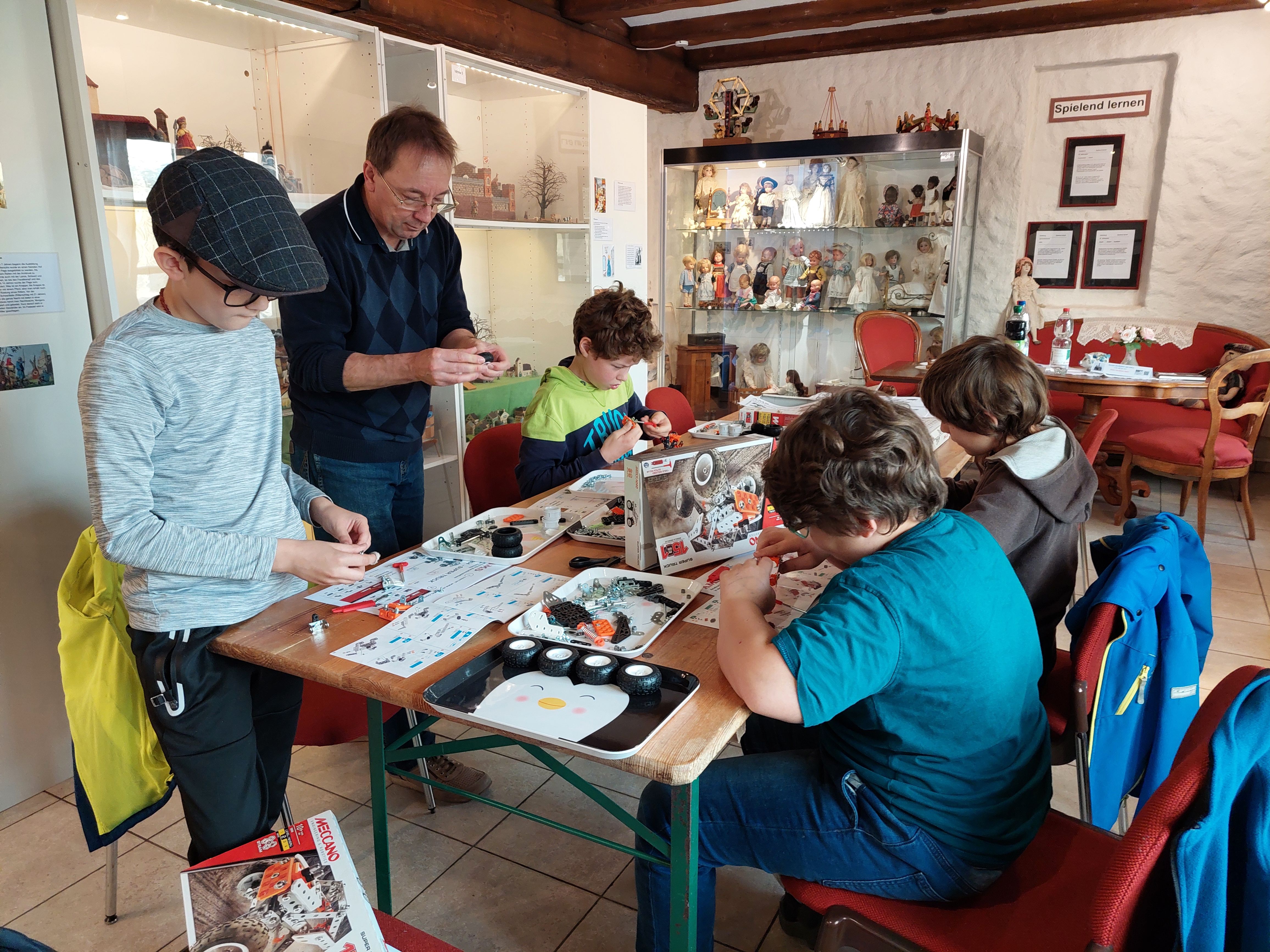 Kinder bauen am Tisch mit Teilen aus dem Metallbaukasten