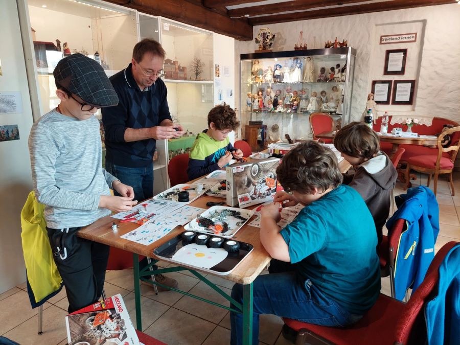 Kinder bauen am Tisch mit Teilen aus dem Metallbaukasten