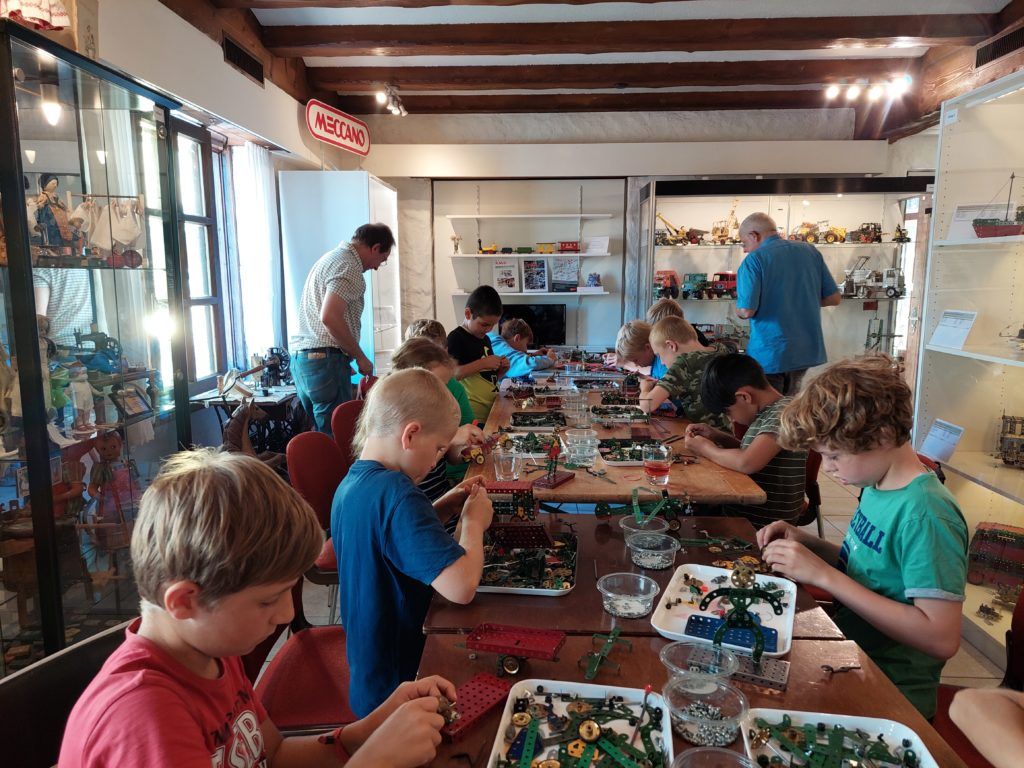 Kinder bauen an einem Tisch, im Hintergrund die Vitrinen des Museums