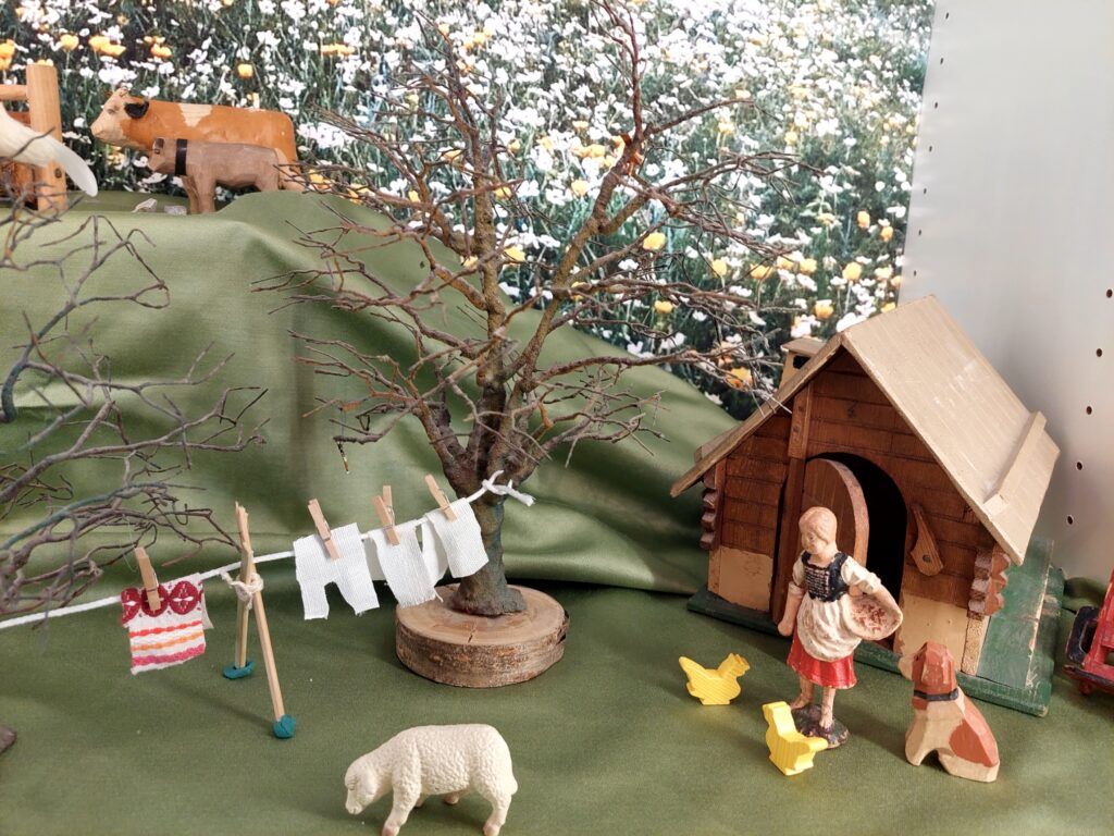 Bauernhofszene mit hölzernem Stall, Kuh, Schaf, Wäscheleine und einer Bauernfigur.