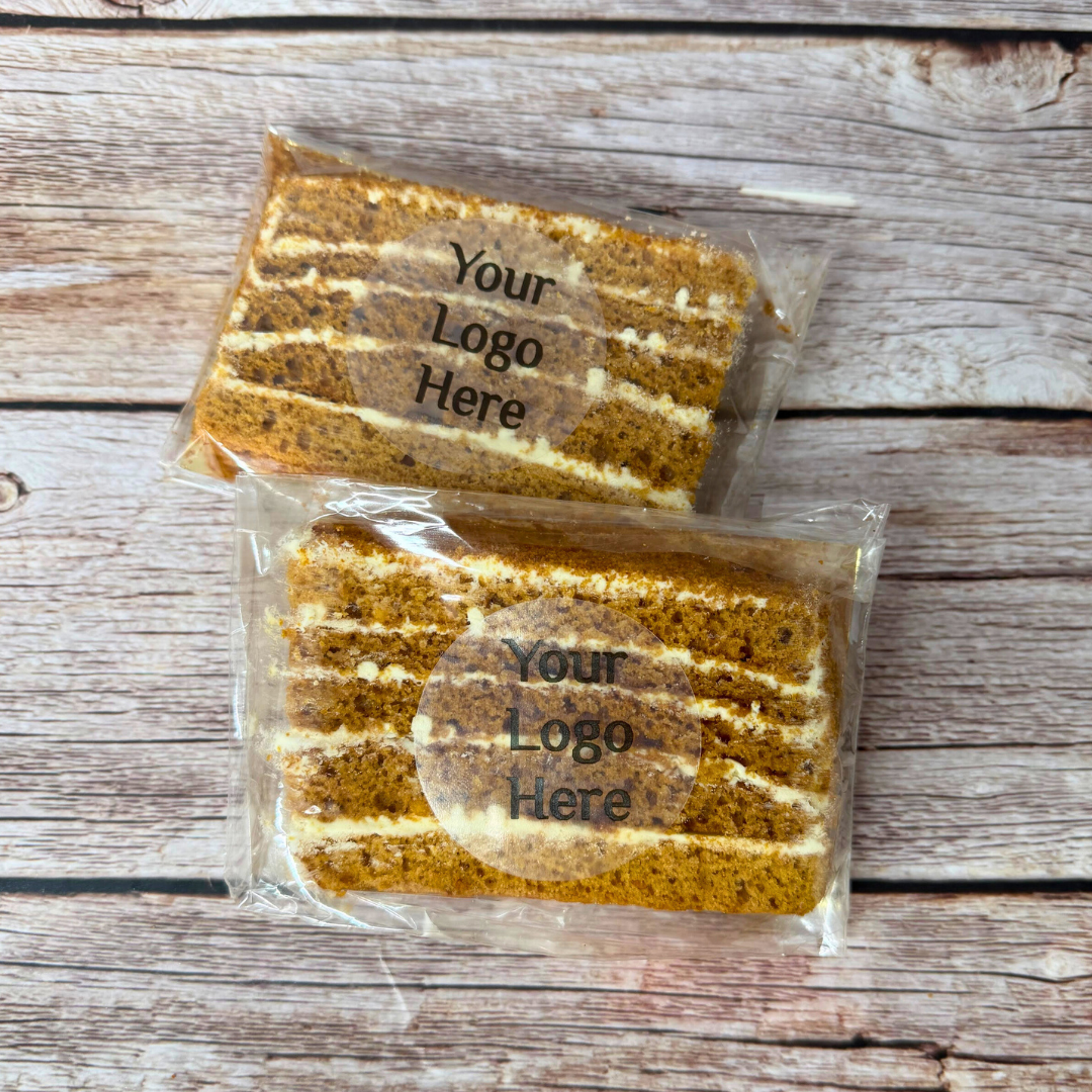 Two individually wrapped slices of Olgish Cakes' authentic Ukrainian Honey Cake (Medovik) featuring a custom branded company logo for corporate exhibition giveaways.