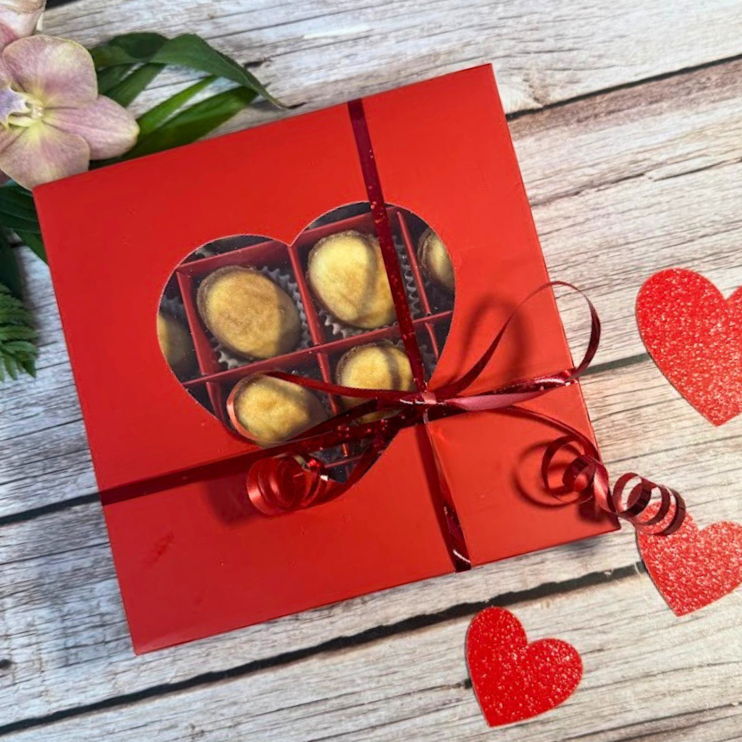 Red Valentine’s biscuit gift box with heart window and ribbon, showing handmade biscuits inside, gift note and shipping included.
